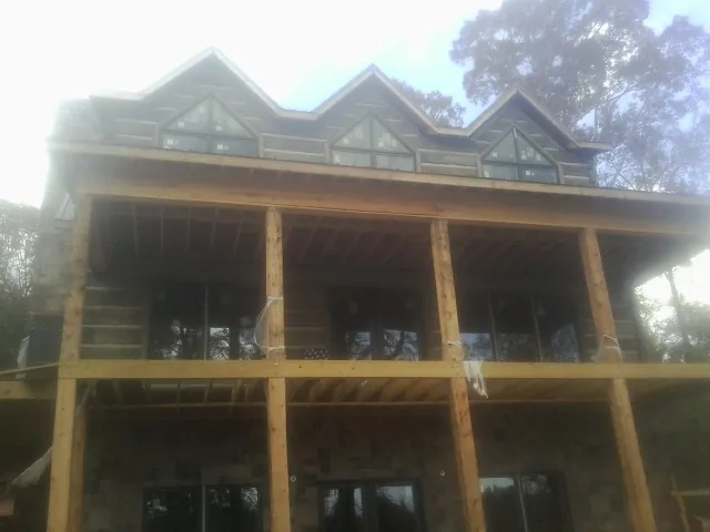 Dormers and porch framing on a large log home under construction — Roof Coating work by our crew in Mount Blanchard