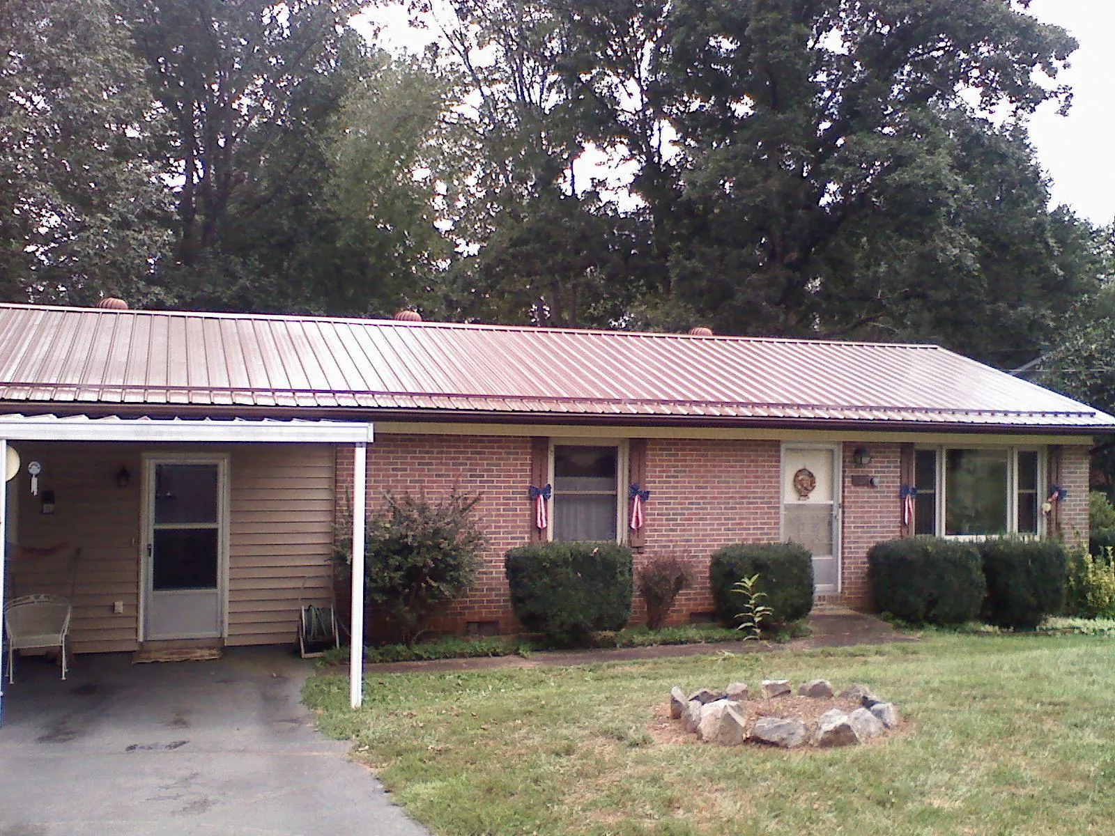 Bronze metal roof and carport on a brick ranch home — Roof Repair work by our crew in Mount Blanchard