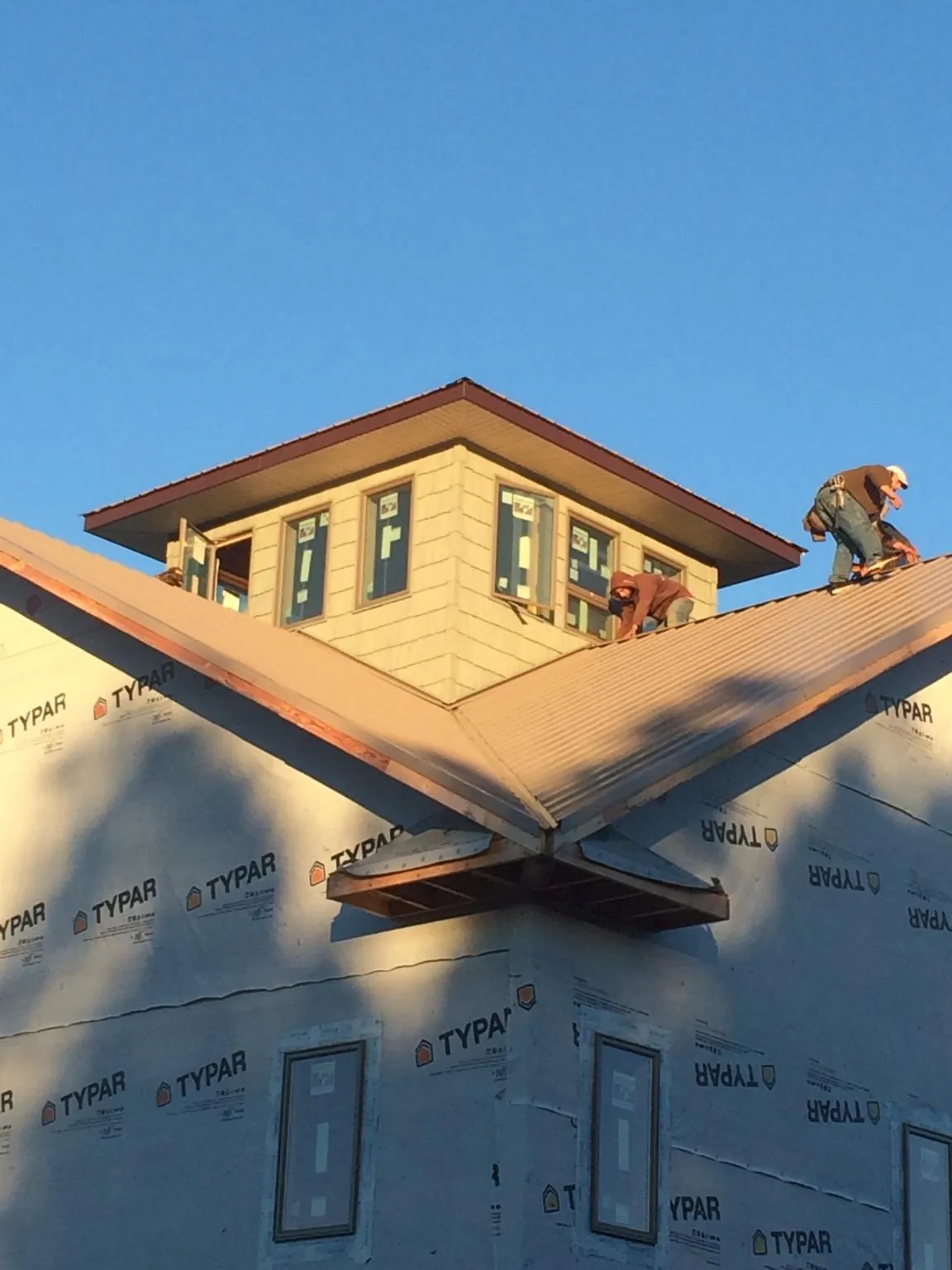 Roofers working around a rooftop cupola on a new metal roof at sunset — Roof Waterproofing in Mount Blanchard by Roofing Brothers